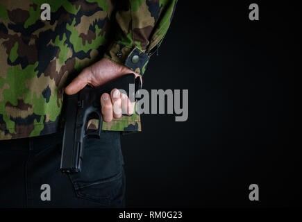 Soldier holds gun behind his back Stock Photo