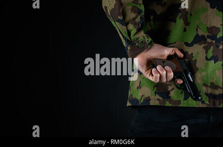 Soldier holds his gun behind his back Stock Photo