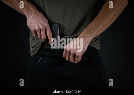 Man try to hide his pistol under his pants Stock Photo