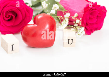 Red heart and roses, and wooden cubes with letters I and U, on white background. I love you concept. Stock Photo