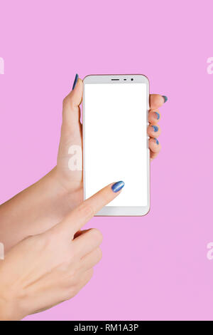 Closeup view of two female hands holding white modern smartphone with blank white screen isolated on violet background. Fingernails with modern glossy Stock Photo
