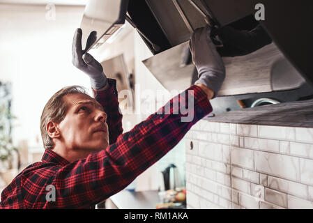 First technical aid. Close-up of young man with kitchen equipment exhaust hood Stock Photo