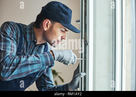 Master's work. Close-up of young handyman setting new windows at the appartment Stock Photo
