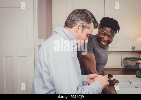 A gay couple sharing stories from their day at work over a slice of toast and a cup of tea and coffee in the evening. Stock Photo