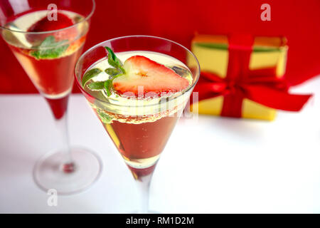 Two champagne glasses with heart shaped strawberry and a gift in the background Valentine's Day concept Stock Photo