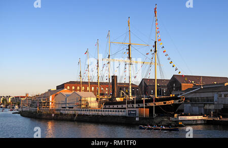 Rowers passing the SS Great Britain, Bristol Docks, South West England at sunset in the evening. Stock Photo