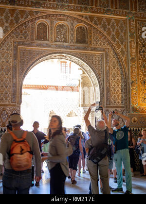 Tourists admire the ceiling of the Ambassador’s Hall (Salon De Embajadores), also known as the Throne Room in the Mudejar palace of the Alcazar in Sev Stock Photo