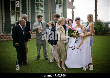 Multi-generational family and friends gathered around a young adult bride as roses are handed out. Stock Photo