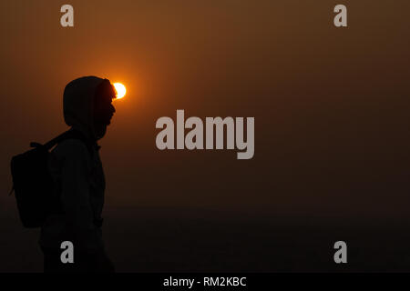 Silhouettes of two hikers with backpacks enjoying sunset view from top of a mountain Stock Photo