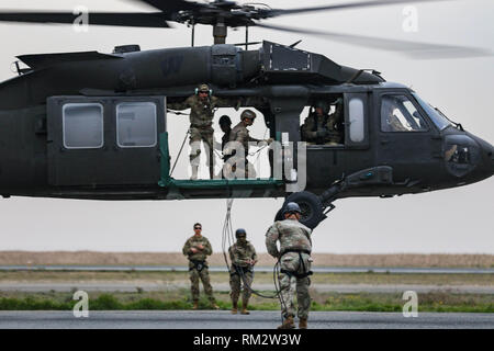 U.S. Army Soldiers lift off in a UH-60 Black Hawk helicopter during fast rope insertion and extraction system training at the Udairi Landing Zone, Camp Buehring, Kuwait, Feb. 9, 2019. The crew members, assigned to the 1st Battalion, 108th Aviation Regiment, Kansas Army National Guard, conducted the training to provide aviation support for an air assault course. Photo was blurred to protect operational security.  (U.S. Army National Guard photo by Sgt. Emily Finn) Stock Photo