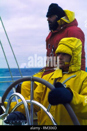 AJAXNETPHOTO. 1978. SOUTHERN OCEAN. - WHITBREAD ROUND WORLD RACE - ICEBERG COUNTRY - JULIAN GILDERSLEEVES STEERS CONDOR (GBR) THROUGH TREACHEROUS ICEBERG WATERS OF THE SOUTHERN OCEAN WHILE CO-SKIPPER LES WILLIAMS KEEPS A SHARP LOOKOUT. PHOTO:GRAHAM CARPENTER/AJAX REF:804582 Stock Photo