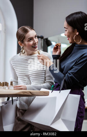 Pretty long-haired pretty woman in a white sweater and a brunette girl looking surprised Stock Photo
