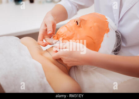 Nice skilled cosmetician taking off a mask Stock Photo