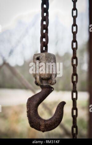 An old rusted chain hoist hangs from the rafter of an abandoned building in Rural Alabama. Stock Photo