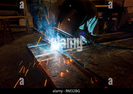 Colorful closeup of welder attaching a piece of metal with sparks flying everywhere Stock Photo