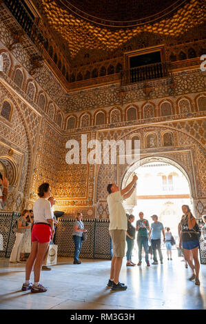 Tourists in the Ambassador’s Hall (Salon De Embajadores), also known as the Throne Room in the Mudejar palace of the Alcazar in Seville, a royal palac Stock Photo