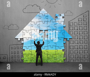 Assembling house shape puzzles on concrete wall Stock Photo