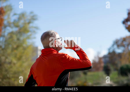 Portrait of a senior runner drinking water after jogging Stock Photo