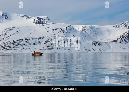 Adventure cruise passengers on a rubber zodiac dingy tour an iceberg in Spitsbergen, Norway in June Stock Photo