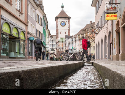 Freiburg im Breisgau - tourist crossing over a bachle - a water filled runnel - in front of the Schwabentor (Swabian city gate), Germany, Europe Stock Photo