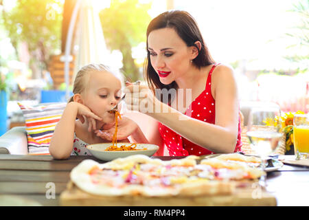 Happy mother and daughter eating spaghetti bolognese in the restaurant together Stock Photo