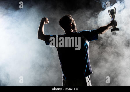 silhouette of man standing with trophy on black with smoke Stock Photo
