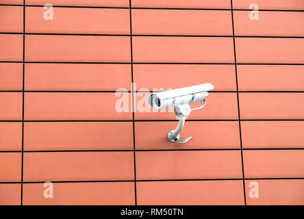 Security camera mounted on modern building orange wall horizontal view closeup Stock Photo