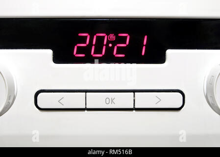 Control panel with red digits on electronic timer display, buttons and round knobs on modern white kitchen electric stove front view closeup Stock Photo