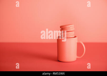 sweet macaroons in cup on Living coral background. Pantone color of the year 2019 concept Stock Photo