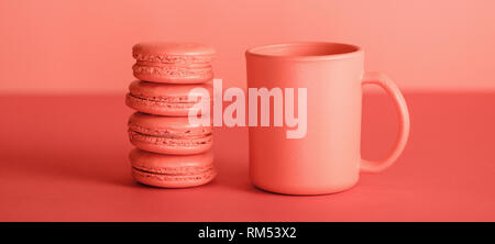 cup of coffee and macaroons in Living coral color. Pantone color of the year 2019 concept Stock Photo