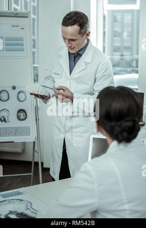 Executive doctor presenting gypsum model of brain during consultation Stock Photo