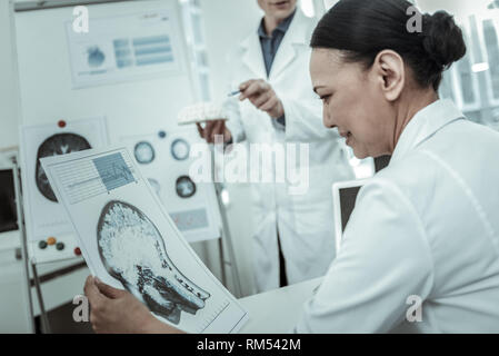 Female doctor during workday attentively looking on the photo Stock Photo