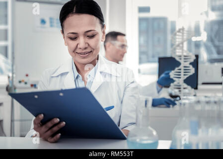 Smiling scientist reading research report with significant results Stock Photo