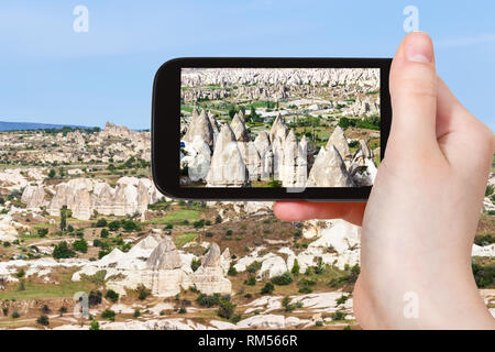 travel concept - tourist photographs of mountain valley with fairy chimney rocks in Goreme National Park in Cappadocia on smartphone in Turkey in spri Stock Photo