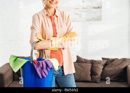 Cropped view of glad woman holding bucket with cleaning supplies Stock Photo