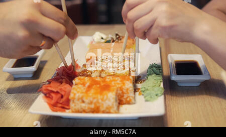 Friends eating sushi rolls in japan restaurant Stock Photo