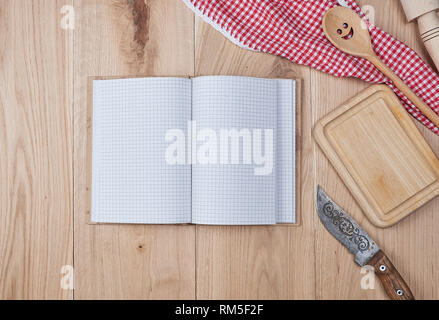 open empty notebook with white sheets and a kitchen wooden spoon on the table, top view Stock Photo