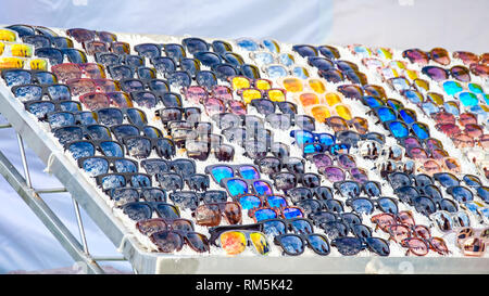 Colorful variety of cheap sunglasses displayed on market stall for sale Stock Photo