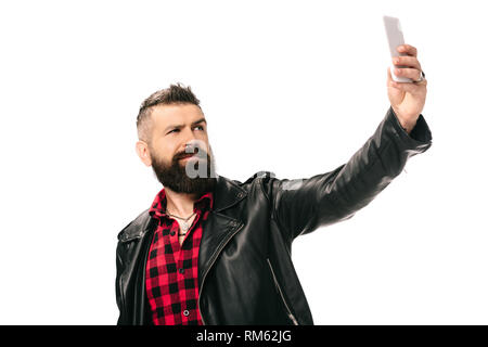 handsome bearded man in black leather jacket taking selfie on smartphone, isolated on white Stock Photo