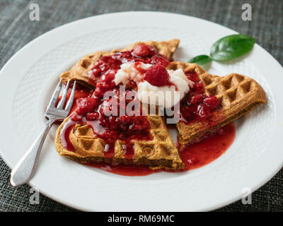Heart shaped vegan beet waffles with a raspberry sauce.