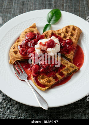 Heart shaped vegan beet waffles with a raspberry sauce.