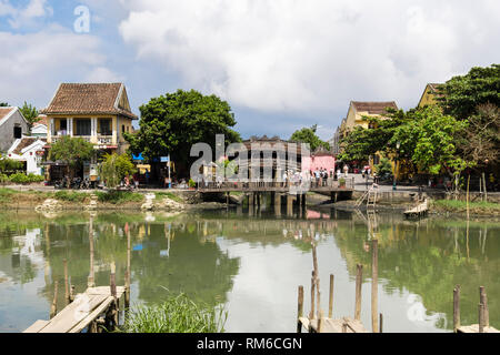 View across Thu Bon River to old Chua Cau or Japanese Covered bridge or Pagoda bridge from An Hoi island. Hoi An, Quảng Nam Province, Vietnam, Asia Stock Photo