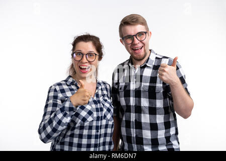 Nerds, geek, bespectacled and funny people concept - a couple of nerds in glasses show us thumbs up on white background Stock Photo