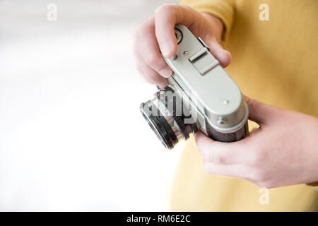 A midsection of a female photographer wearing yellow and holding a vintage, 35mm camera with copy space in a hobby lifestyle image Stock Photo