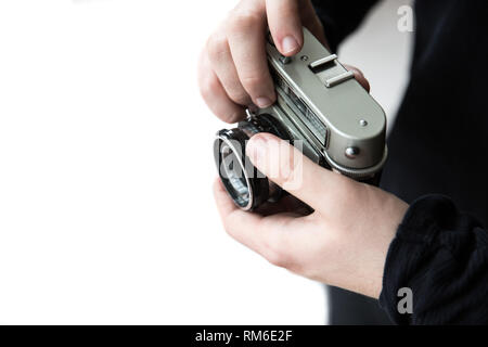 A midsection of a male photographer focussing a lens whilst holding a vintage, 35mm camera with copy space on a white background Stock Photo