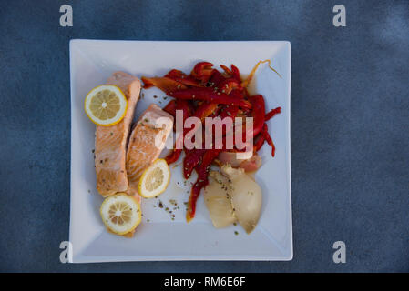 grilled salmon with roasted red peppers, onion and lemon slices Stock Photo