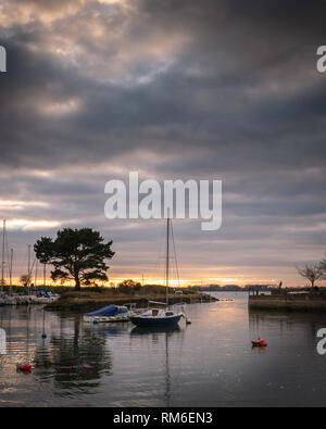 sail boats harbor reflecting on the water during a cloudy sunset Stock Photo