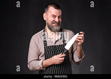 Portrait of a handsome male chef holding knife checking its edge. Stock Photo