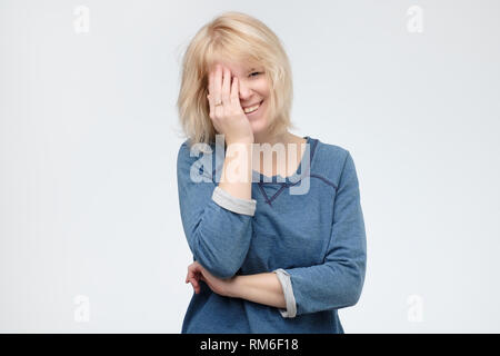 Good looking young female giggles joyfully, covers mouth as tries stop laughing. Stock Photo