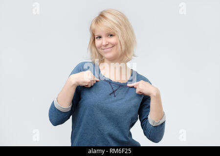 Girl with pleasant appearance, points at herself as asks she really won prize Stock Photo